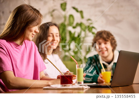 Friends enjoying colorful smoothies while working together at office. Friends enjoying colorful smoothies while working together at office. 135558455