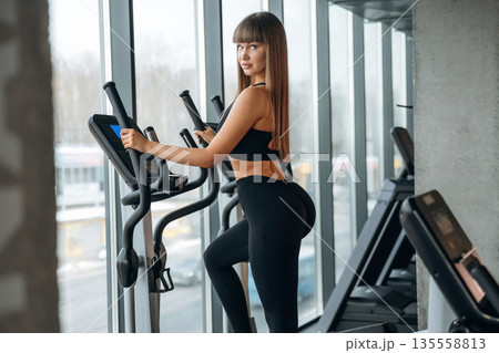 Using modern equipment, cardio concept. Young woman is in the gym Using modern equipment, cardio concept. Young woman is in the gym 135558813
