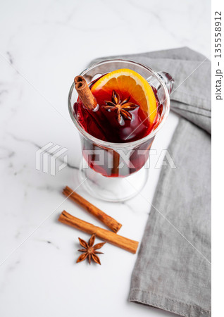 Glass of mulled wine, orange, cinnamon, and star anise on a marble background with spice 135558912