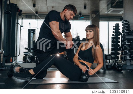 Trainer is helping. Man and woman are in the gym together 135558914