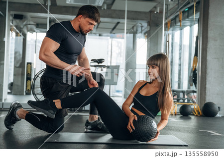 On the mat with ball. Man and woman are in the gym together On the mat with ball. Man and woman are in the gym together 135558950
