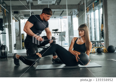 On the mat with ball. Man and woman are in the gym together On the mat with ball. Man and woman are in the gym together 135558952