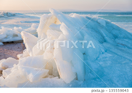 Shoreline with stacked ice slabs at sunset, winter landscape and broken crystalline layers. Shoreline with stacked ice slabs at sunset, winter landscape and broken crystalline layers. 135559043