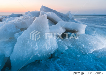 Ice slabs on a frozen coastline at sunset with evening light and deep blue shadows. Ice slabs on a frozen coastline at sunset with evening light and deep blue shadows. 135559047