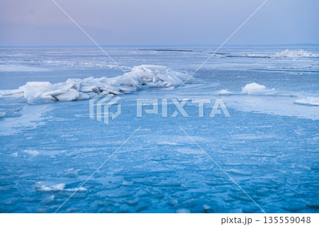 Frozen north sea with cracked ice and pastel sunset sky in winter stillness. Frozen north sea with cracked ice and pastel sunset sky in winter stillness. 135559048