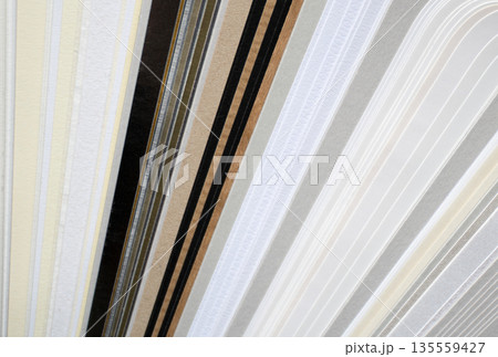 Closeup of layered print production sampler with textured paper swatches in various neutral tones and metallic Closeup of layered print production sampler with textured paper swatches in various neutral tones and metallic 135559427