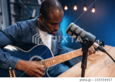 Blue acoustic guitar. Man is doing podcast in the studio Blue acoustic guitar. Man is doing podcast in the studio 135559457