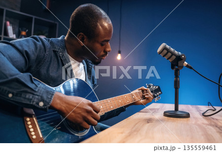 Singer songwriter with guitar. Man is doing podcast in the studio Singer songwriter with guitar. Man is doing podcast in the studio 135559461