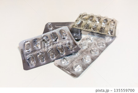 Old used metal pills and capsules blisters packaging. Empty, opened with no pills and capsules. Healthcare and medicines concept. 135559700