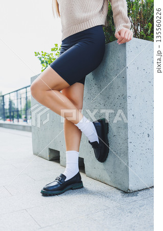 Female legs in leather shoes, white socks with and black moccasins, black shorts, fashion details Female legs in leather shoes, white socks with and black moccasins, black shorts, fashion details 135560226