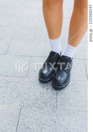 Female legs in leather shoes, white socks with and black moccasins, black shorts, fashion details Female legs in leather shoes, white socks with and black moccasins, black shorts, fashion details 135560247