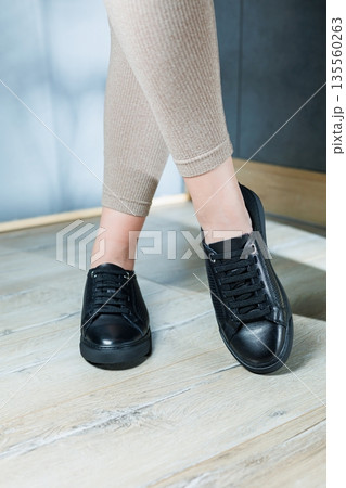 Collection of women's shoes. Black leather sneakers on women's feet. Female feet in comfortable casual sandals Collection of women's shoes. Black leather sneakers on women's feet. Female feet in comfortable casual sandals 135560263