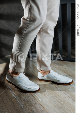 Male legs in leather summer shoes. Comfortable men's white moccasins without laces. Casual men's moccasins 135560298