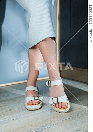 White leather sandals on women's feet. Female feet in comfortable casual sandals 135560321