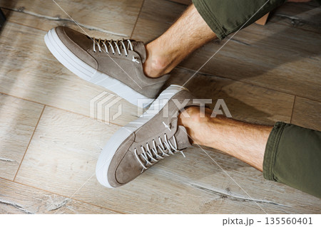 Collection of men's summer shoes. Male legs in beige leather sneakers. Men's classic shoes. 135560401