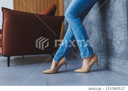 Beautiful slender female legs in classic beige shoes with thin heels. The concept of successful sales and big discounts Beautiful slender female legs in classic beige shoes with thin heels. The concept of successful sales and big discounts 135560527