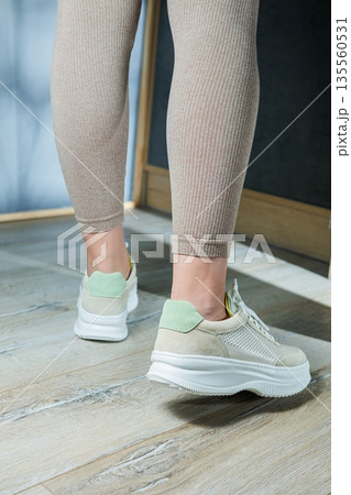 Close-up of female legs in leather sneakers on feet. Modern seasonal collection of stylish sneakers. Women's fashion. 135560531