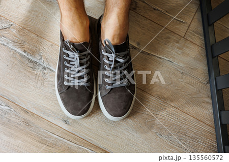Male legs in gray casual sneakers. Comfortable men's summer shoes. 135560572