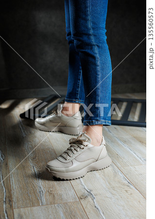 Beige women's sneakers. Collection of women's leather shoes. Female legs in leather beige casual sneakers. Stylish women's sneakers. 135560573