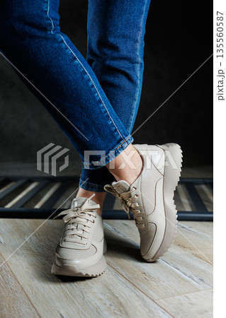 Beige women's sneakers. Collection of women's leather shoes. Female legs in leather beige casual sneakers. Stylish women's sneakers. Beige women's sneakers. Collection of women's leather shoes. Female legs in leather beige casual sneakers. Stylish women's sneakers. 135560587