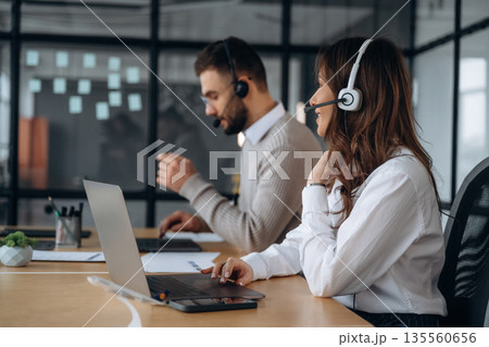 Call center, in headphones. Man and woman are working in the office Call center, in headphones. Man and woman are working in the office 135560656