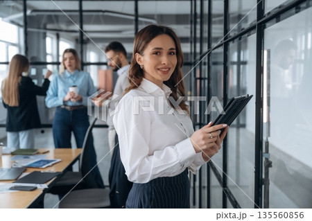 Digital tablet in hands of woman. Business people are working in the office Digital tablet in hands of woman. Business people are working in the office 135560856