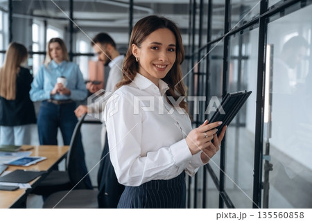 Digital tablet in hands of woman. Business people are working in the office Digital tablet in hands of woman. Business people are working in the office 135560858