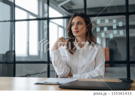 Sitting and thinking. Beautiful woman is in the office 135561433