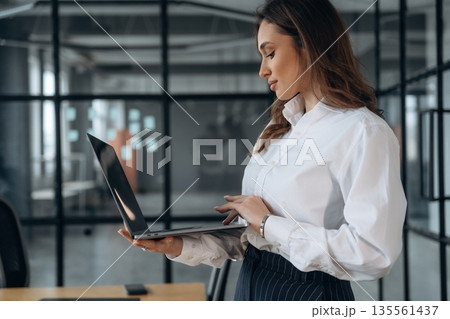 With a laptop. Beautiful woman is in the office With a laptop. Beautiful woman is in the office 135561437