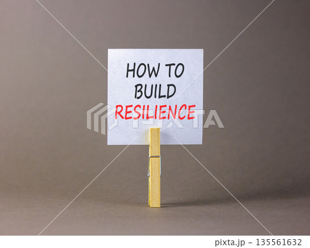 How to build resilience symbol. Concept words How to build resilience on beautiful white paper on wooden clothespins. Beautiful grey background. Business how to build resilience concept. Copy space. How to build resilience symbol. Concept words How to build resilience on beautiful white paper on wooden clothespins. Beautiful grey background. Business how to build resilience concept. Copy space. 135561632