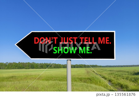 Tell or show symbol. Concept words Do not just tell me, show me beautiful black road sign. Beautiful blue sky green field background. Business tell or show concept. Copy space. 135561876