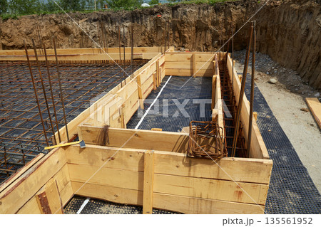 Steel reinforcement is placed in wooden molds and formwork on a construction site Steel reinforcement is placed in wooden molds and formwork on a construction site 135561952
