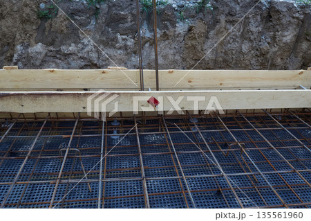 Steel reinforcement is placed in wooden molds and formwork on a construction site  135561960