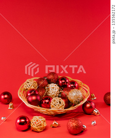 Wicker Basket Filled with Christmas Ornaments on Red Background Wicker Basket Filled with Christmas Ornaments on Red Background 135562172