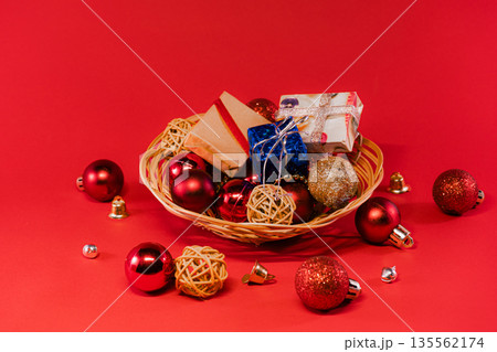 Wicker Basket Filled with Christmas Ornaments on Red Background 135562174