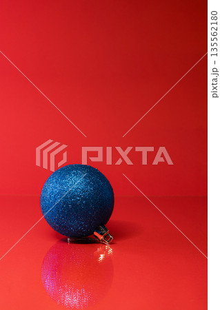 Single Blue Christmas Ornament on Vibrant Red Background Single Blue Christmas Ornament on Vibrant Red Background 135562180