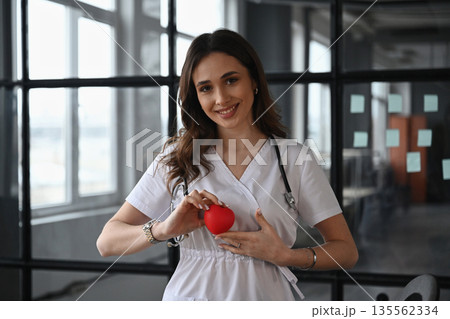 Cardiologist is holding toy heart. Woman doctor is in the office Cardiologist is holding toy heart. Woman doctor is in the office 135562334