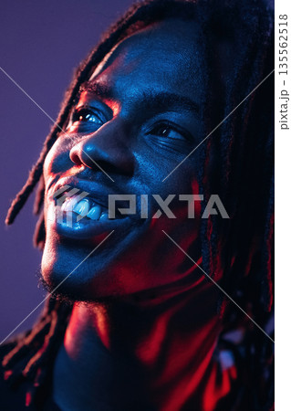 Smiling, positive facial expression. African American guy is studio with neon lighting 135562518