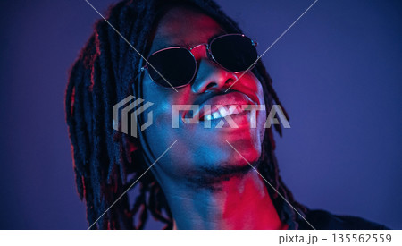 In sunglasses. African American guy is studio with neon lighting 135562559