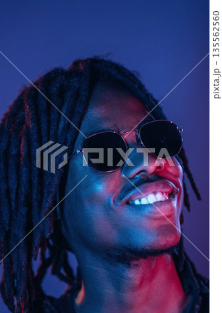 In sunglasses. African American guy is studio with neon lighting 135562560