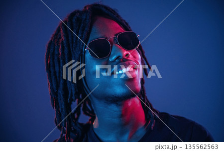 In sunglasses. African American guy is studio with neon lighting 135562563