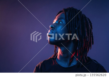 Focused close up view. African American guy is studio with neon lighting 135562620