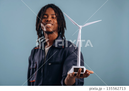 Wind turbine model in hand. Black man is in the studio against soft background Wind turbine model in hand. Black man is in the studio against soft background 135562713