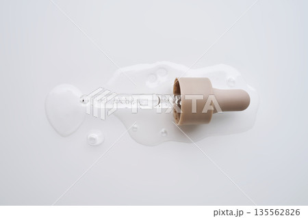 Skin care liquid dropping from pipette on white background Skin care liquid dropping from pipette on white background 135562826