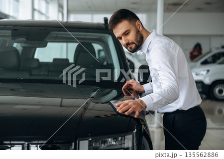 Checking the surface. Dealership worker is near the car Checking the surface. Dealership worker is near the car 135562886