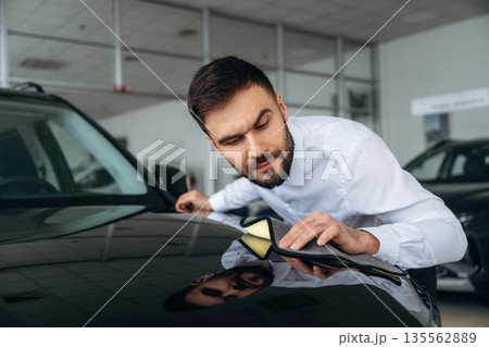 Checking the surface. Dealership worker is near the car Checking the surface. Dealership worker is near the car 135562889