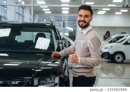 Polished surface. Man is with the car in dealership Polished surface. Man is with the car in dealership 135562949