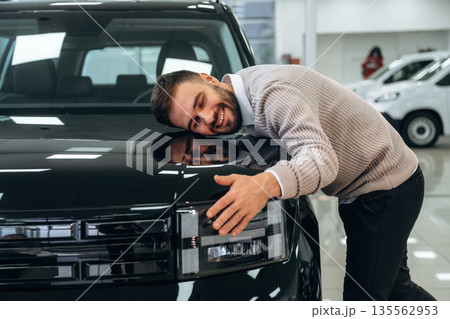Embracing the vehicle. Man is with the car in dealership 135562953