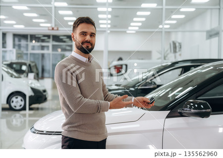 Keys for new automobile. Man is with the car in dealership Keys for new automobile. Man is with the car in dealership 135562960