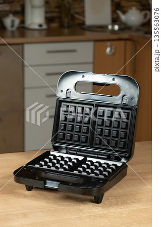 Electric Waffle Maker Appliance Ready for Use on a Wooden Kitchen Countertop. Electric Waffle Maker Appliance Ready for Use on a Wooden Kitchen Countertop. 135563076